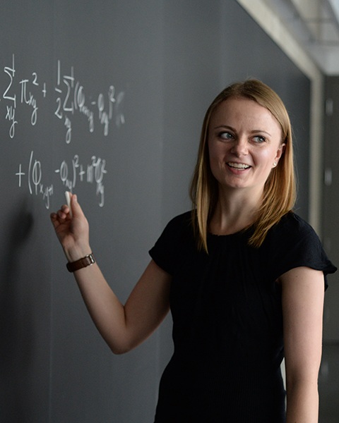 Young woman writing equations on a blackboard
