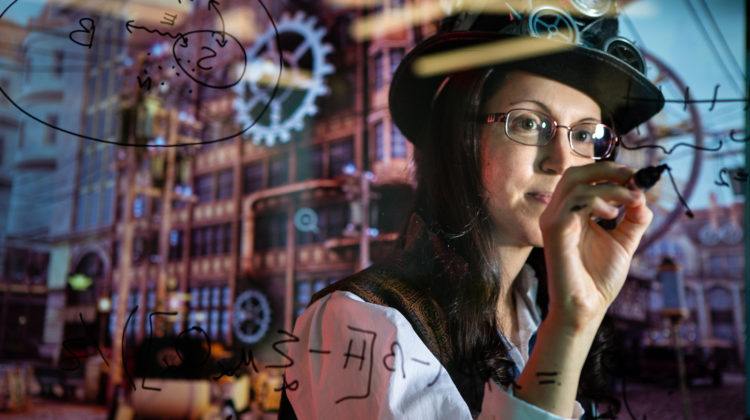 Researcher Nicole Yunger Halpern writes equations on a transparent board between her and the camera. She is wearing a top hat with gears on it.