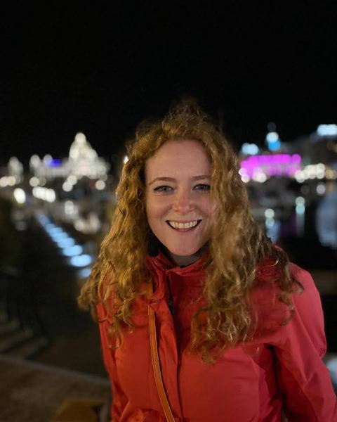 Portrait of a woman at night with city lights behind her