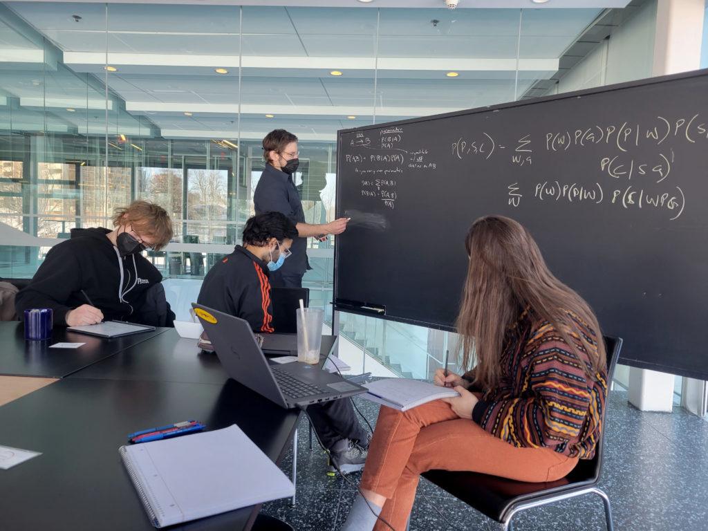 Group of students and teacher working on physics problems together