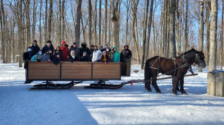 A group of people in a horse drawn sled in a forest during winter