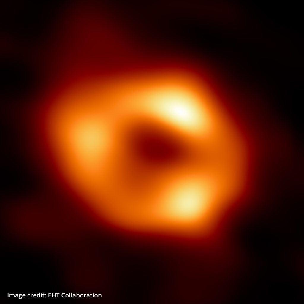 Scientific image of black hole - black background with light yellow/orange forming a ring