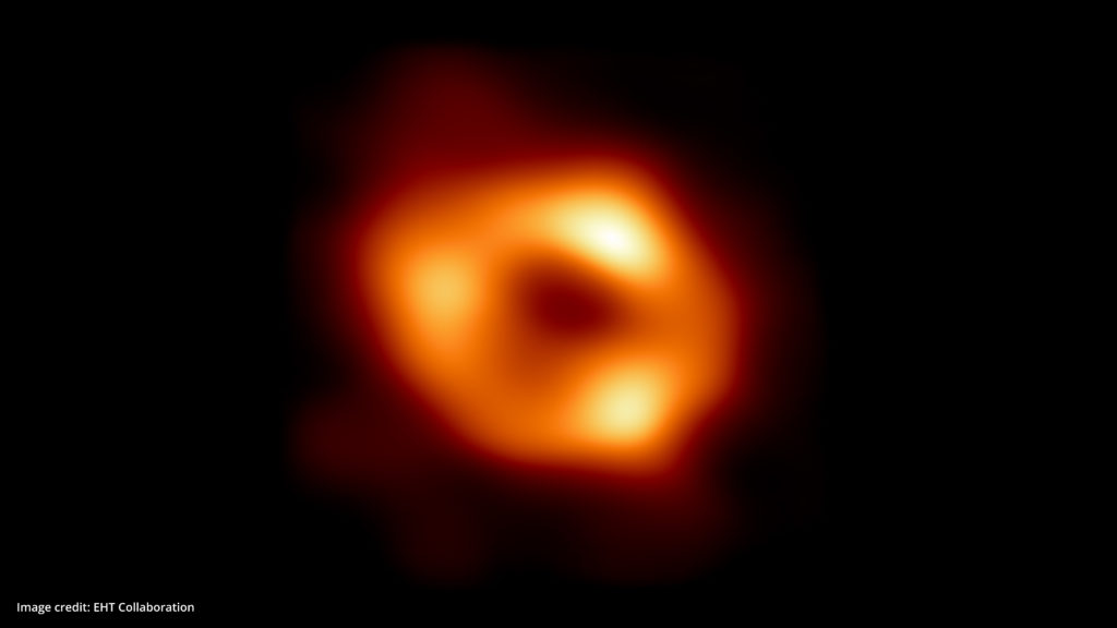 Image scientifique d'un trou noir -- anneau lumineux jaune et eorangé sur un fond noir