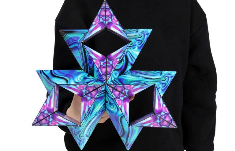 Person wearing black sweater holding a geometric multicoloured shape piece